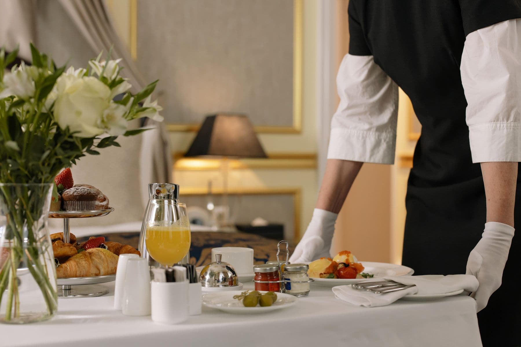 A hospitality professional carefully setting breakfast for a guest